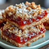 Warm Guava Jam Bars are cut into squares, revealing layers of buttery oat crust, sticky guava center, and crunchy roasted macadamia nut crumble.