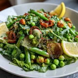 Bright lemon vinaigrette spring salad with radishes and peas, bursting with fresh greens and crisp vegetables in a zesty dressing.