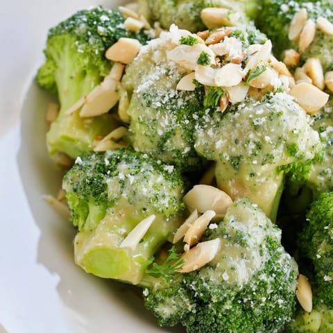 Vibrant green broccoli florets tossed in creamy garlic Parmesan dressing, garnished with toasted almonds and fresh parsley.