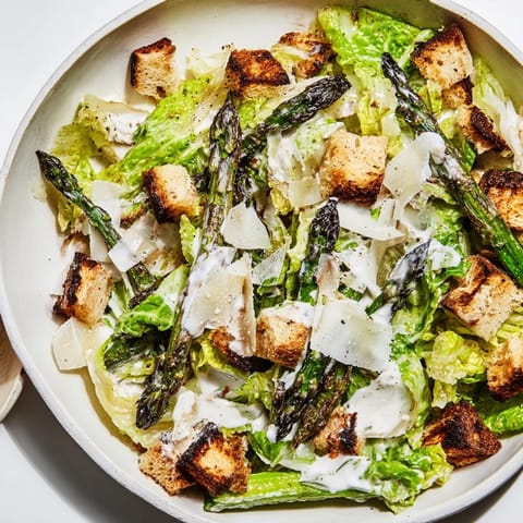 Golden-brown roasted asparagus spears arranged over crisp romaine lettuce, drizzled with tangy yogurt Caesar dressing and topped with crunchy homemade croutons
