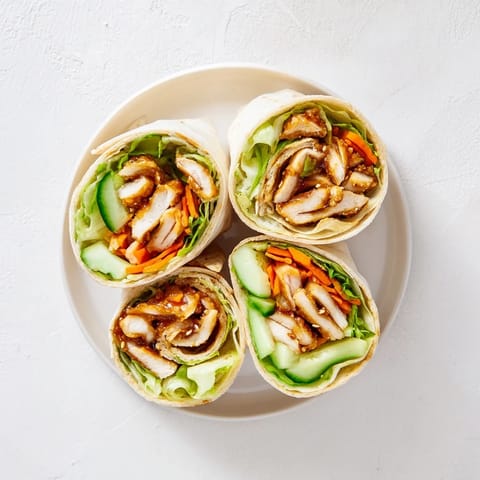 Freshly prepared Honey Chili Crunch Chicken Wrap with juicy pan-seared chicken and vibrant crisp vegetables on a soft tortilla.