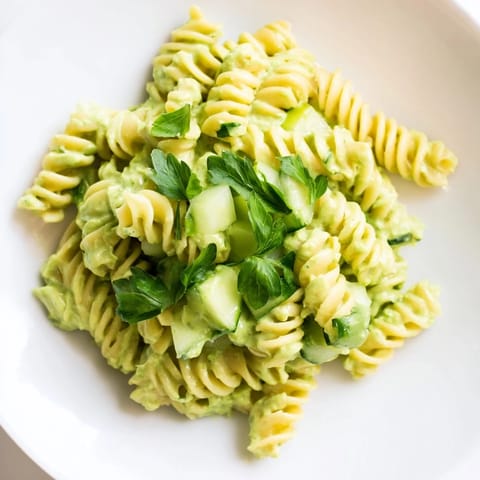 Bright green Green Goddess Pasta Salad with creamy dressing, crisp cucumber, and fresh herbs in a white bowl.