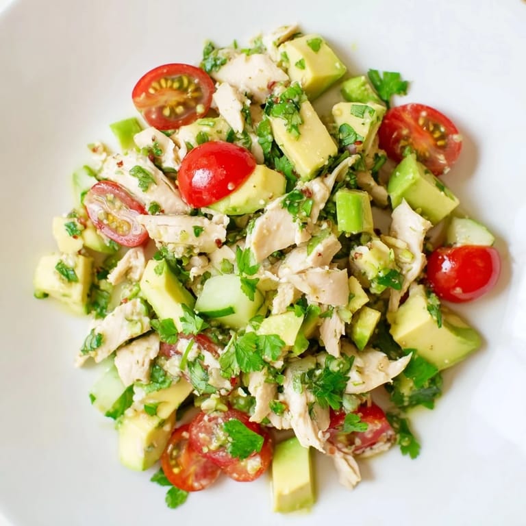 A chilled bowl of avocado chicken salad with red onion and cucumber, ready to serve as a light gluten-free lunch.