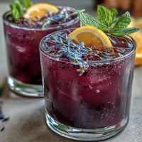 Vibrant purple lavender lemonade refresher with fresh lemon slices and lavender sprigs in a glass pitcher.